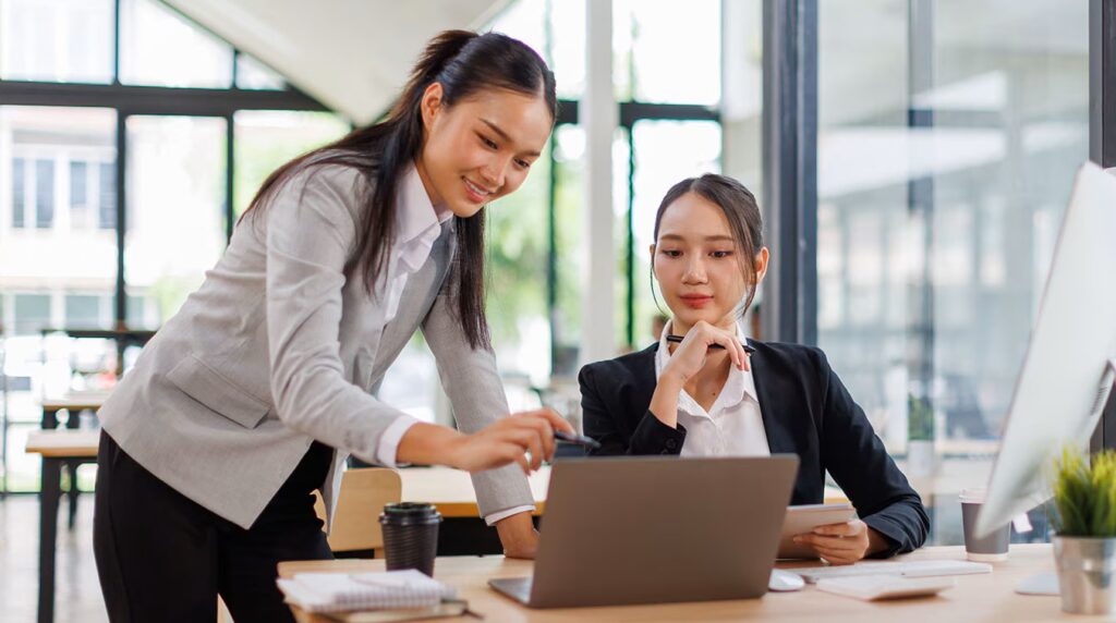 two asian women looking at computer