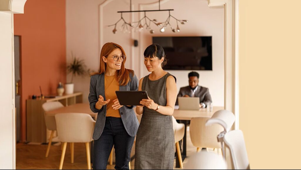 two women standing looking at a tablet