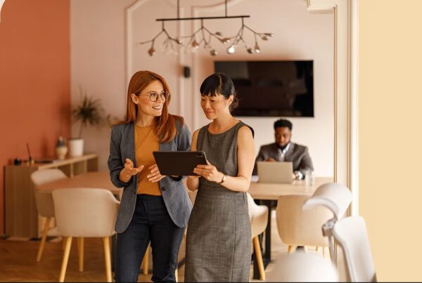 two women standing looking at a tablet