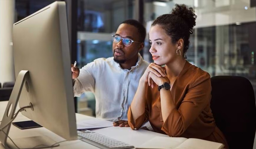 man and a woman looking computer screen