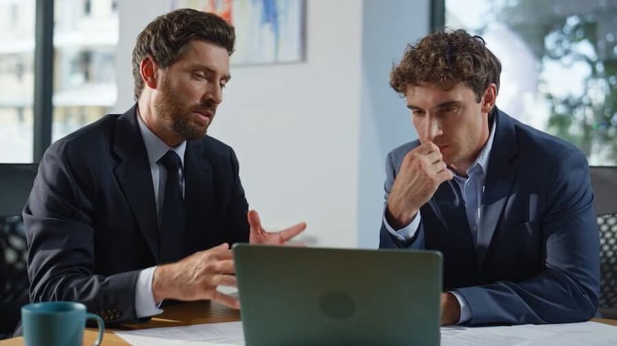 two gentlemen sitting looking at computer