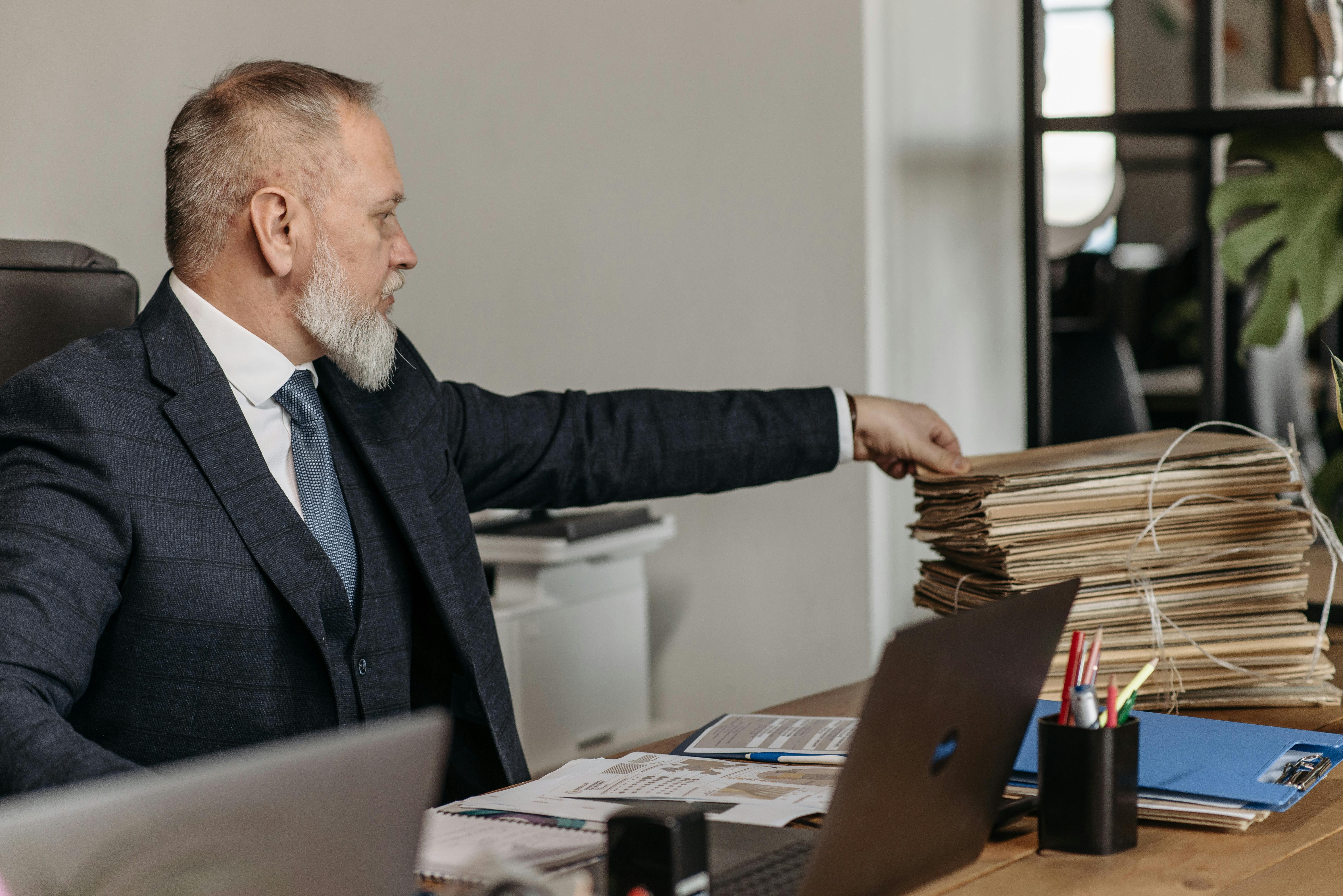 man at desk with stack of folders