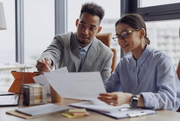 two people sitting at desk looking over paperwork