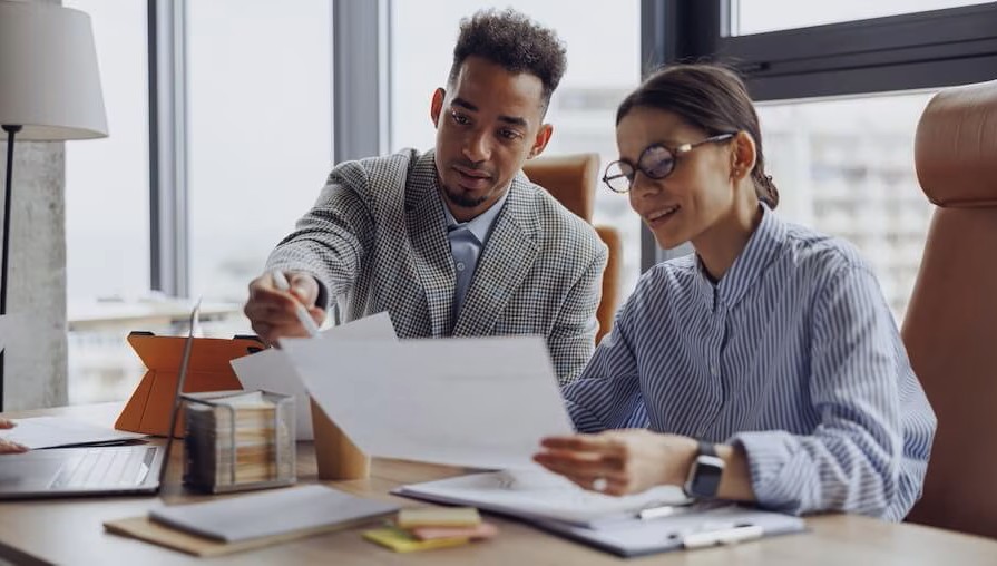 two people sitting at desk looking over paperwork